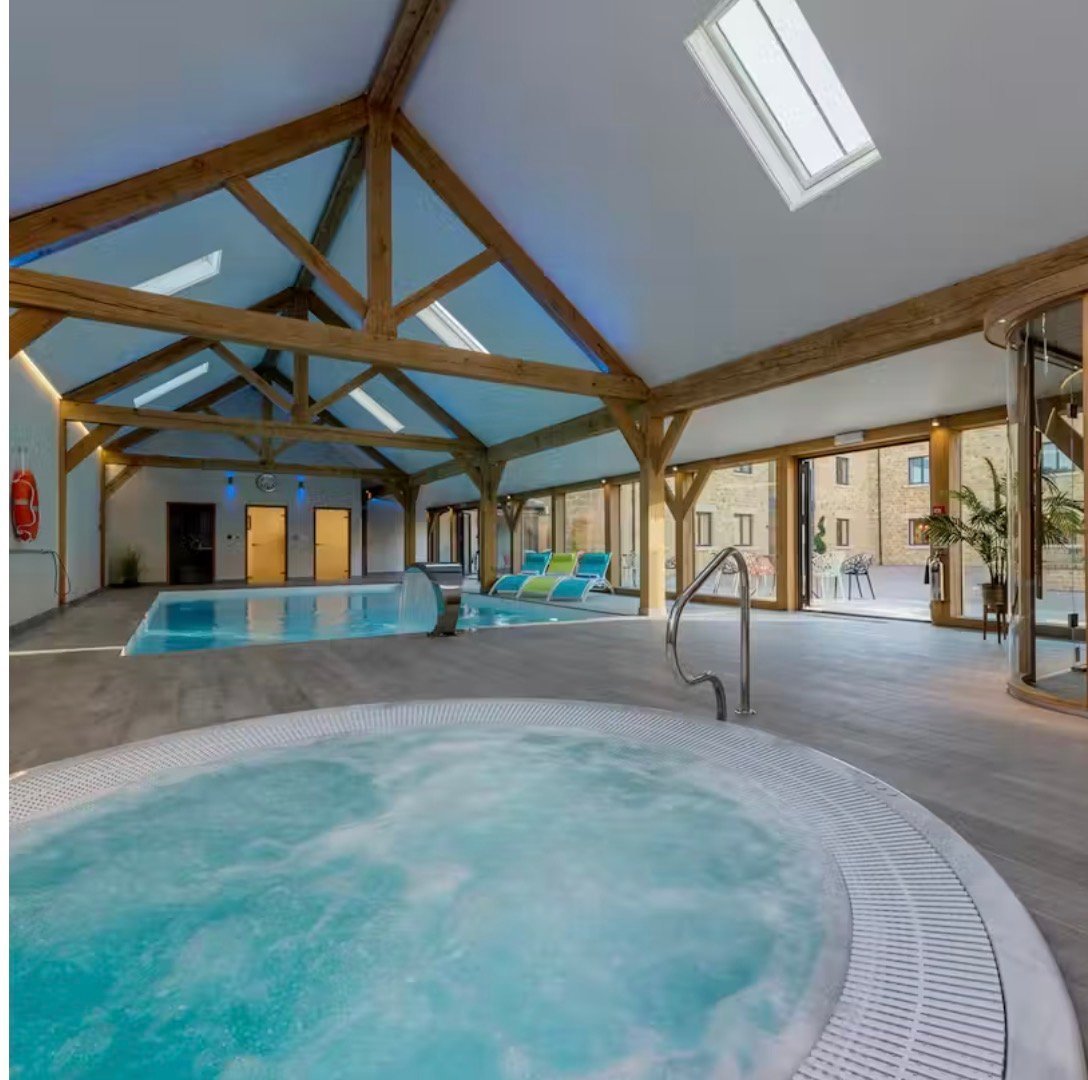Spacious indoor leisure center with swimming pool, exposed wooden beams, and skylights